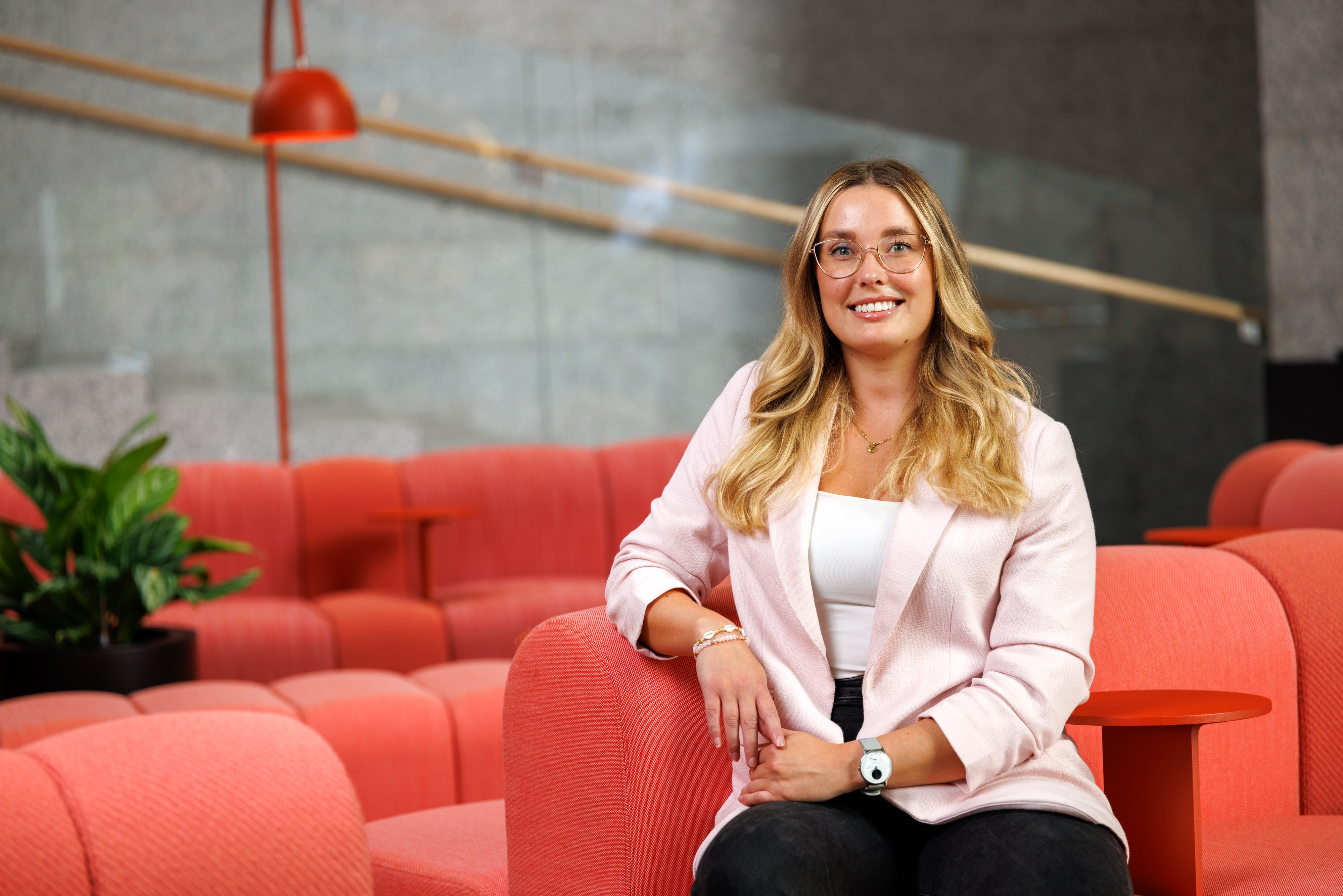 Henkilö istuu toimiston sohvalla ja hymyilee, Controller Susanna Komi