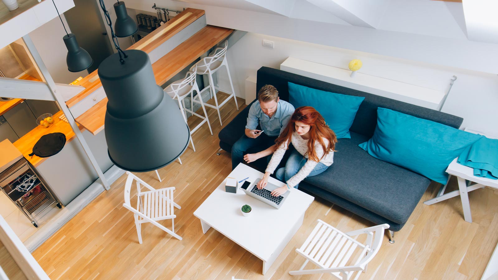 Pariskunta istuu sohvalla, kuvattu katonrajasta.