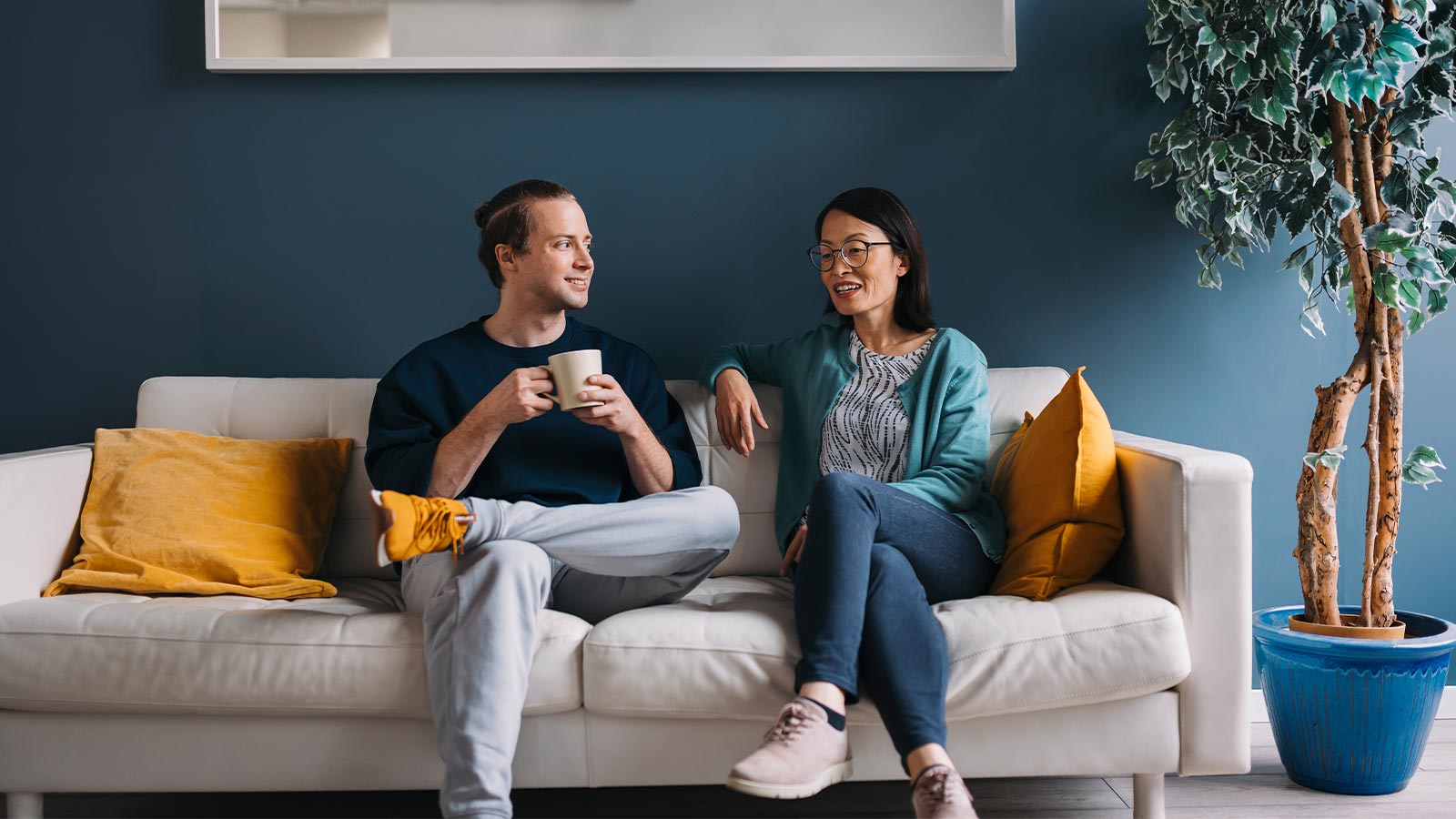 Kuvassa kaksi henkilöä istuvat sohvalla ja keskustelevat aiheesta työhyvinvointi.