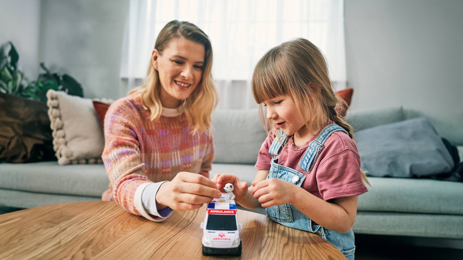 Aikuinen ja lapsi leikkivät pienoisambulanssilla.