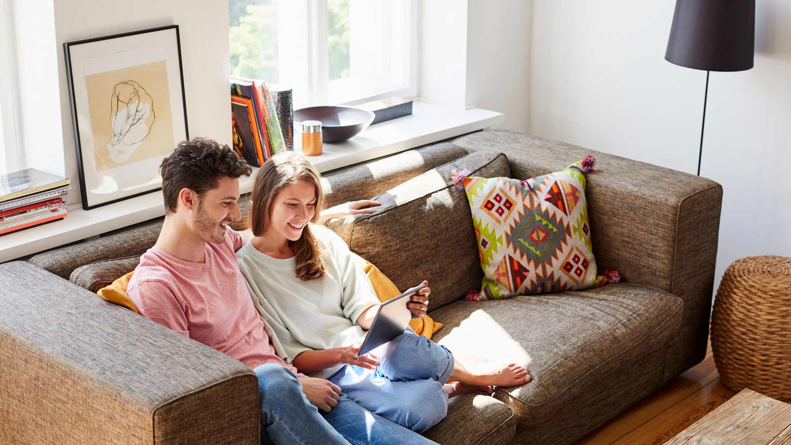 Pariskunta istuu sohvalla ja katsoo mobiililaitetta.