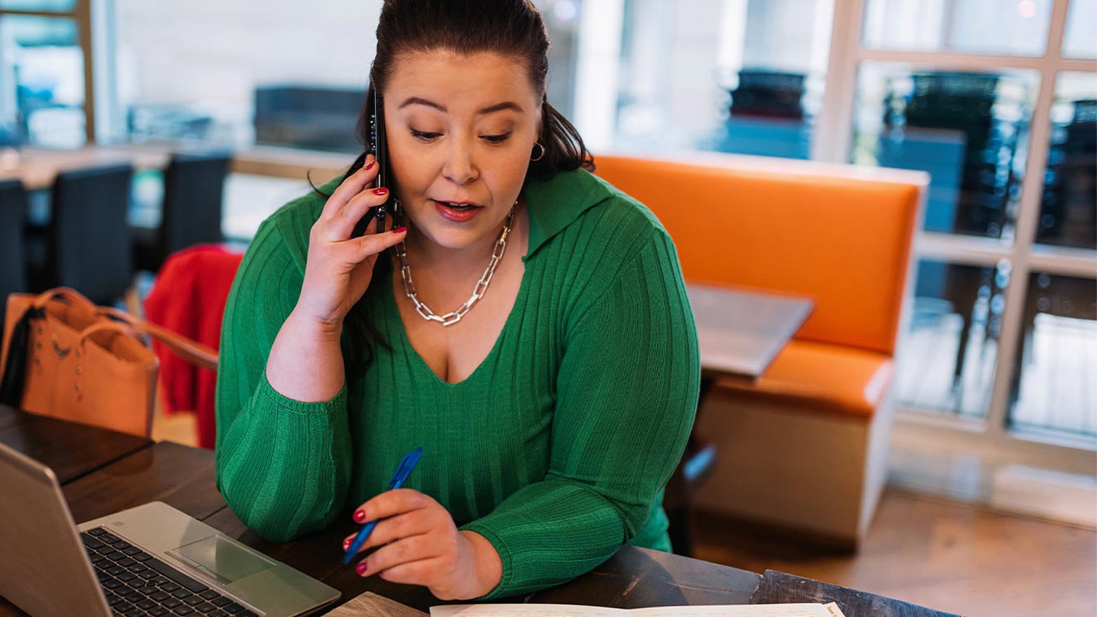 Nainen istuu kahvilassa ja tutkii koneellaan netistä yritysvakuutusten hinnat.