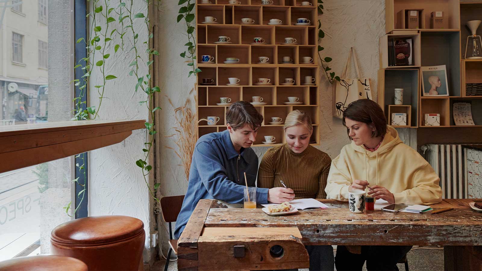 Kaksi naista ja mies kahvilan pöydässä käymässä läpi toiminimen vakuutuksia.