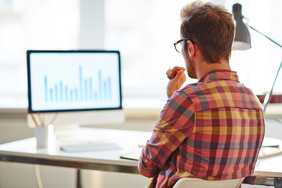 Mies istuu pohtivan näköisenä tietokoneen ääressä