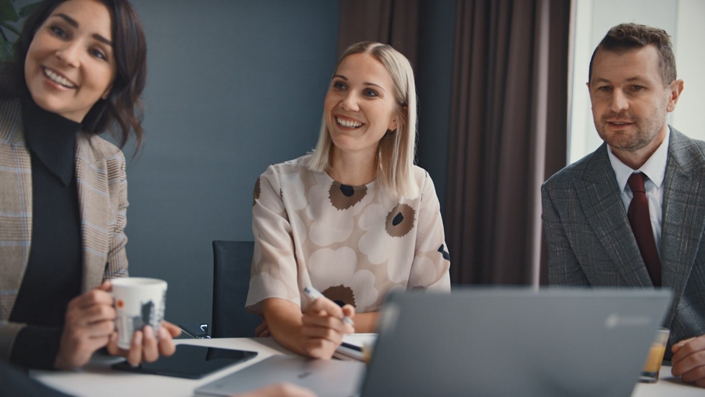 Kaksi naista ja mies hymyilevät