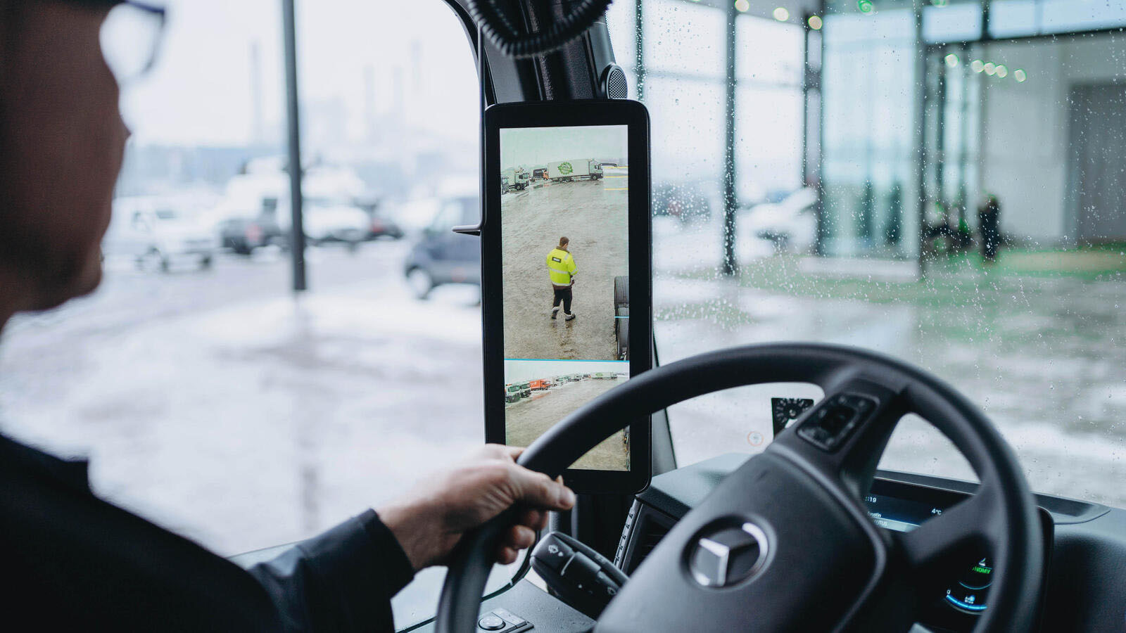 Kuvassa näkyy kuorma-auton peruutuspeili ja näkymä parkkipaikalle.