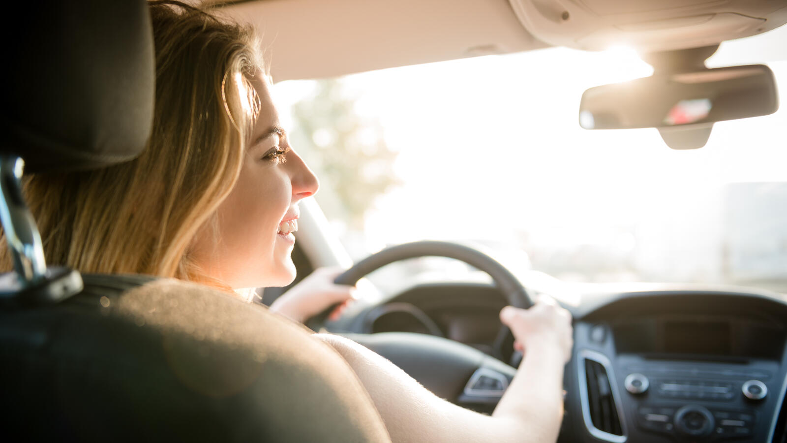 Kuvassa on iloinen taksikuski, jonka ajoneuvon ja liiketoiminnan turvaa taksialan vakuutukset