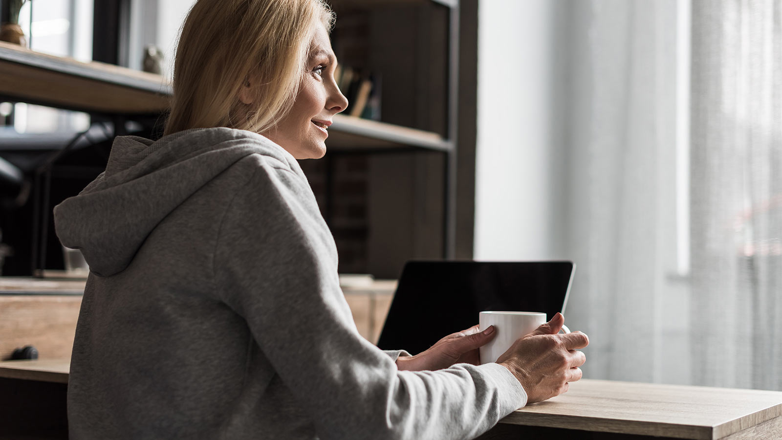 Nainen valkoisessa paidassa hymyilemässä, koska hän tietää että Potilasvakuutus on kunnossa.