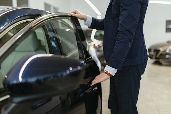 Ihminen avaa auton ovea autokaupassa