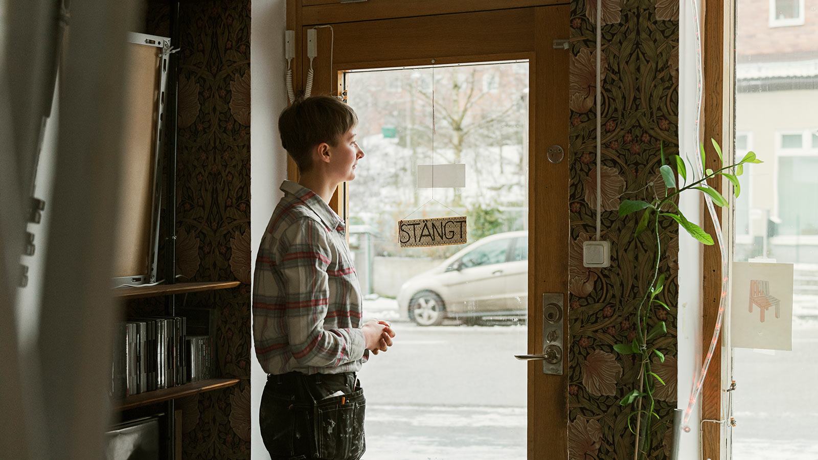 Nainen katsoo ulos ikkunasta ja pohtii murtoriskiä liiketiloissaan.