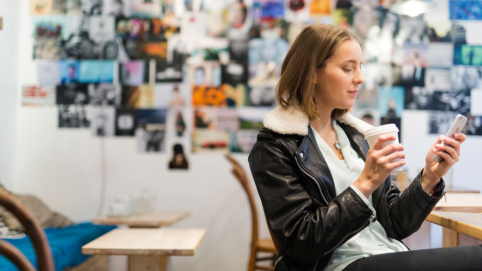 Nainen katsoo puhelinta kahvilassa.