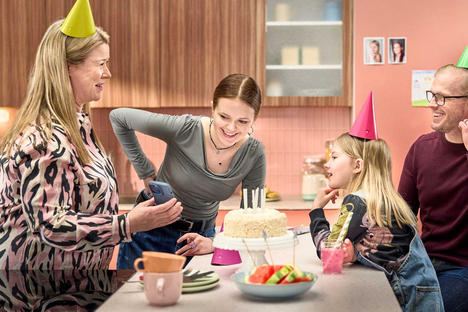 Perhe kokoontunut keittiöön juhlimaan lapsen syntymäpäivää