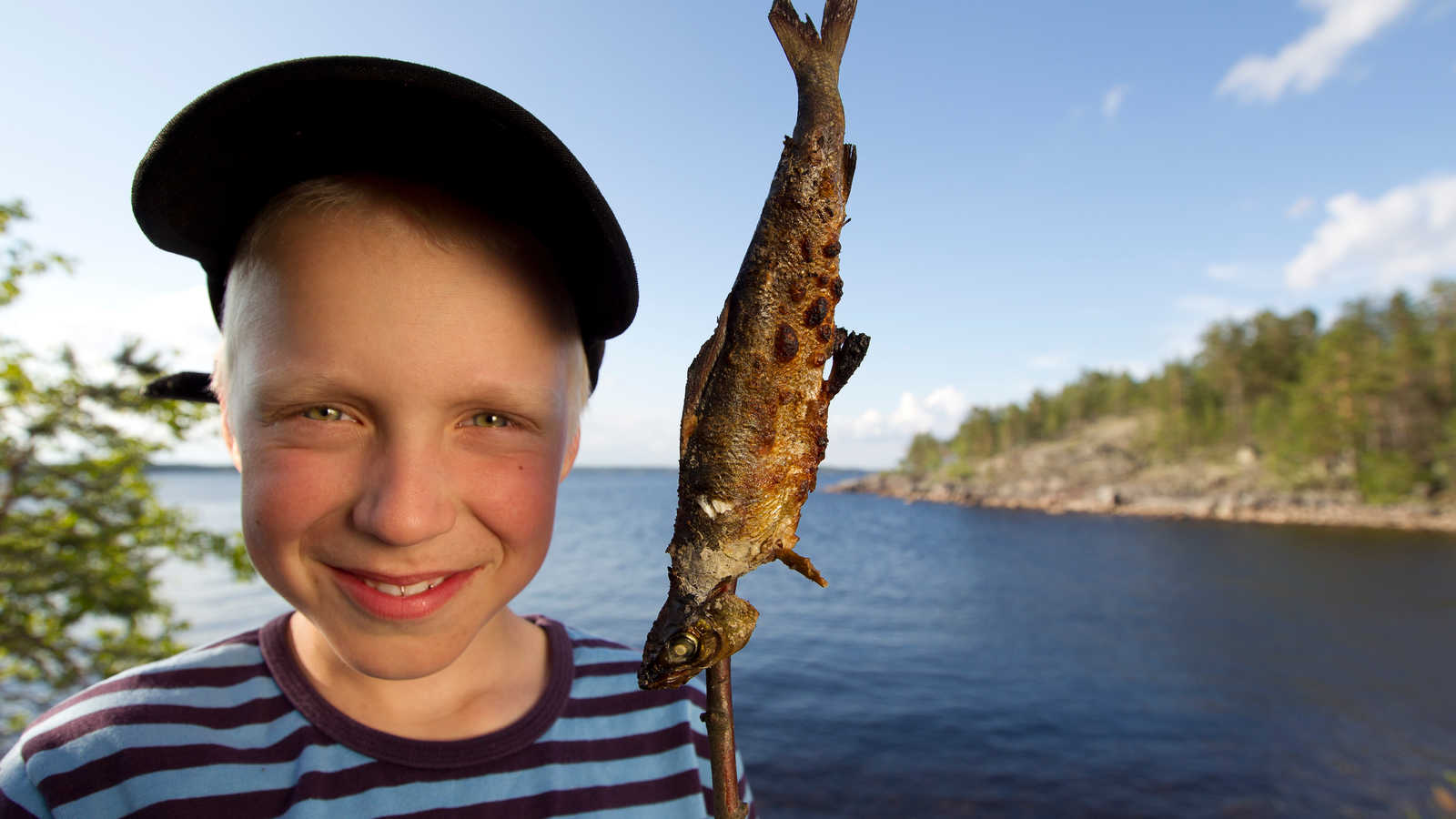 Poika järvellä kalasaaliin kanssa