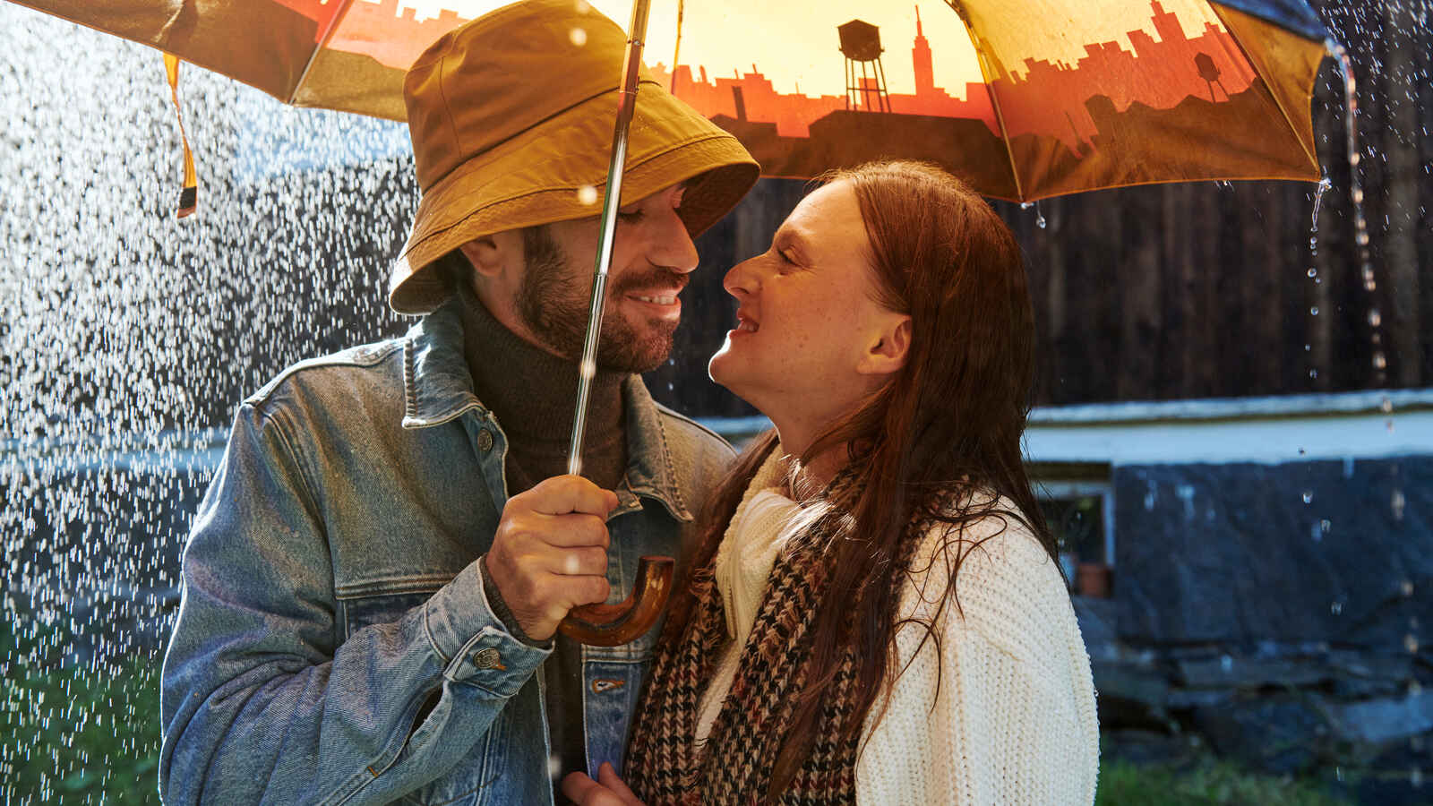 Pariskunta sateelta suojassa sateenvarjon alla