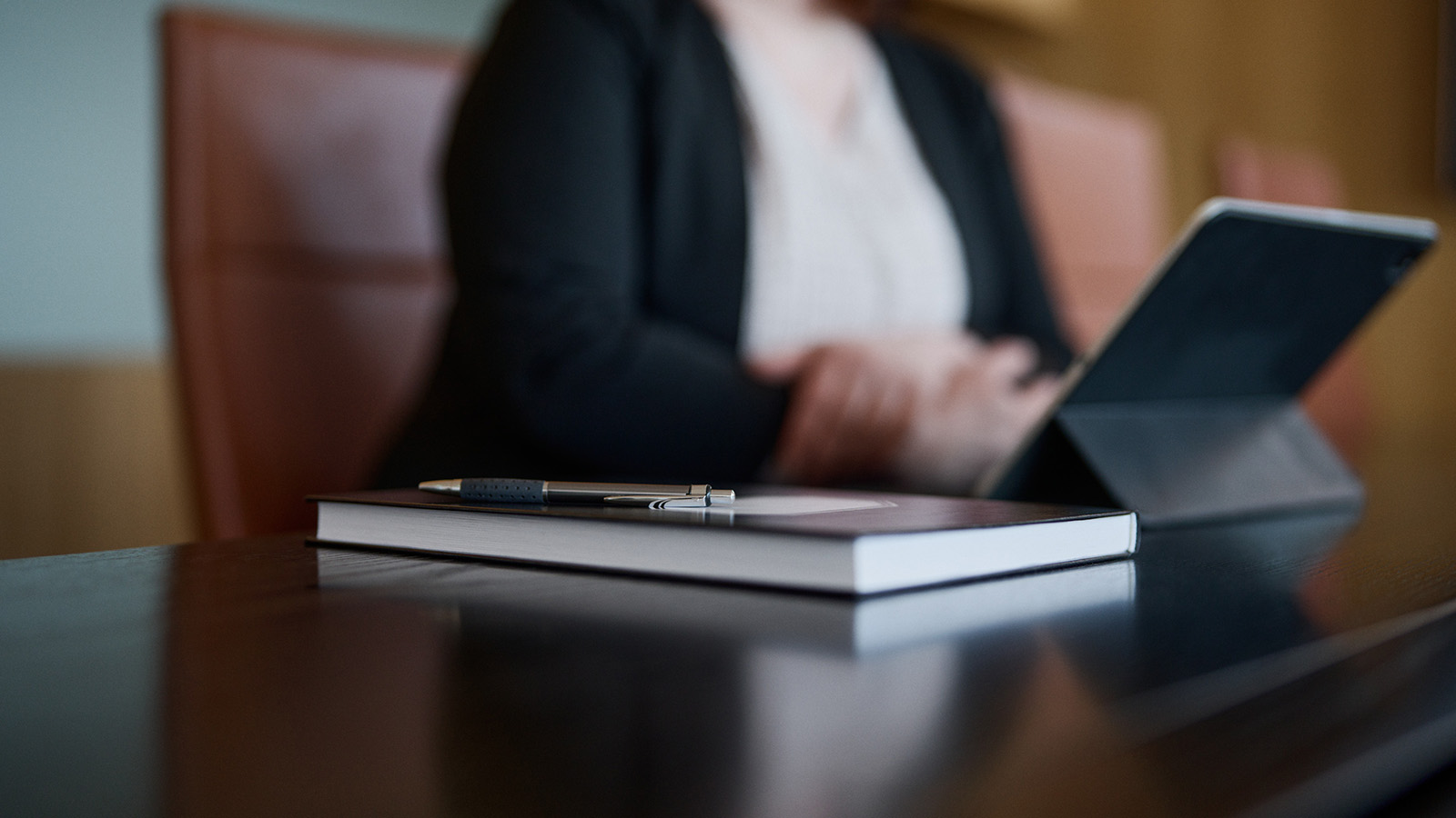 Musta muistikirja ja kannettava tietokone neuvotteluhuoneen pöydällä